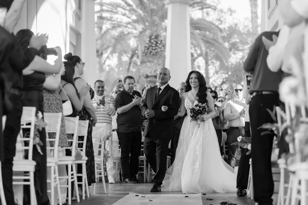 Bride walking down aisle with father at Mandalay Bay Valley of the Falls wedding black and white
