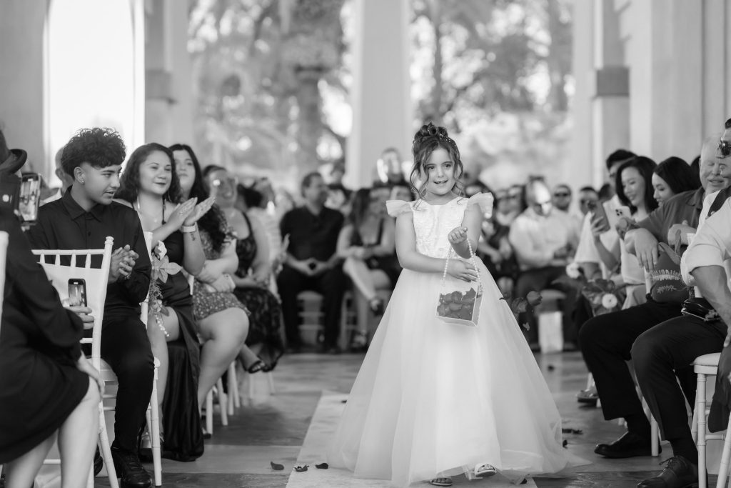 Flower girl walking down aisle at Mandalay Bay Valley of the Falls wedding ceremony black and white