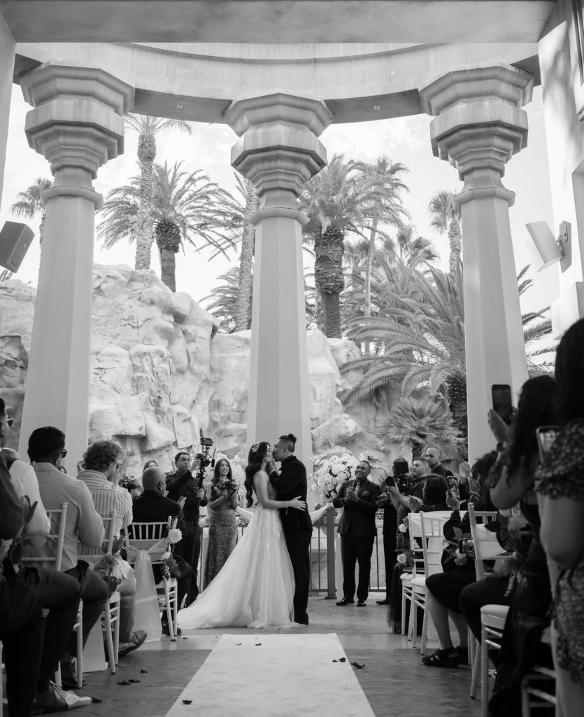 Bride and groom kissing during ceremony at Mandalay Bay Valley of the Falls black and white