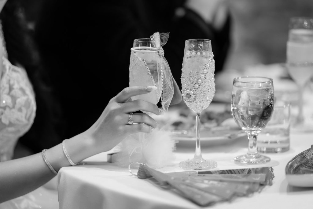 Bride holding champagne glass during wedding toast in black and white