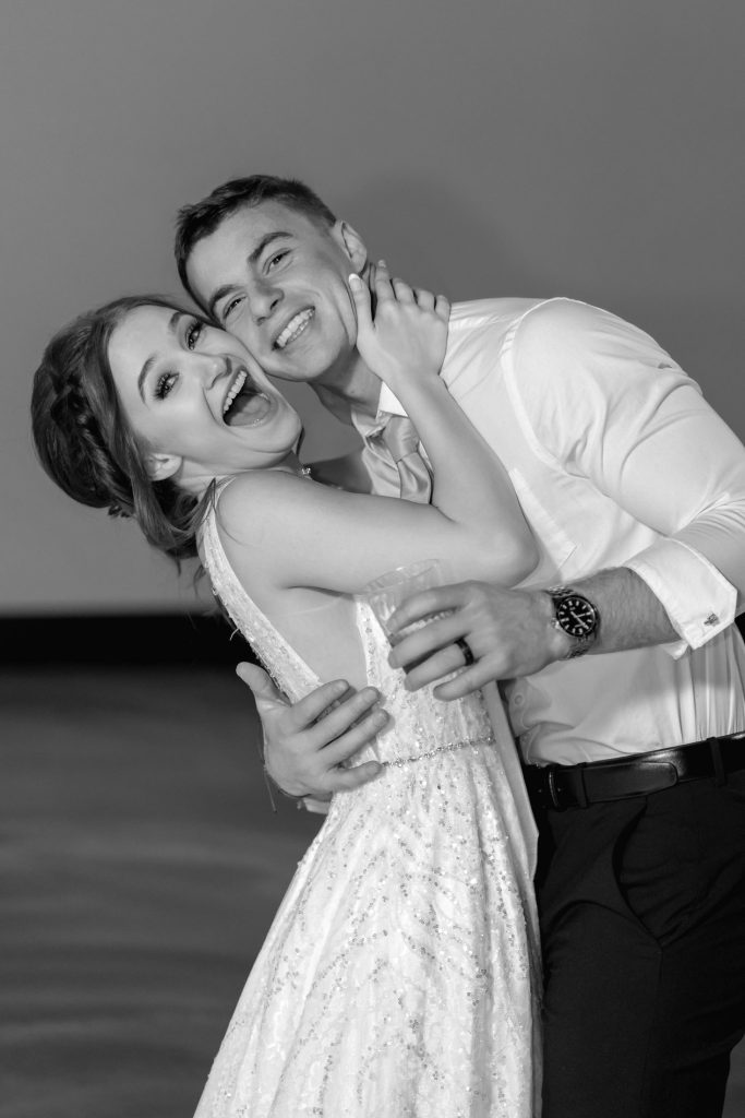 Bride and groom laughing candidly during wedding celebration in black and white