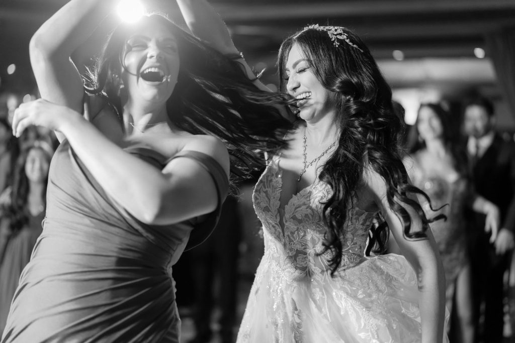 Bride and guest dancing energetically on wedding dance floor in black and white