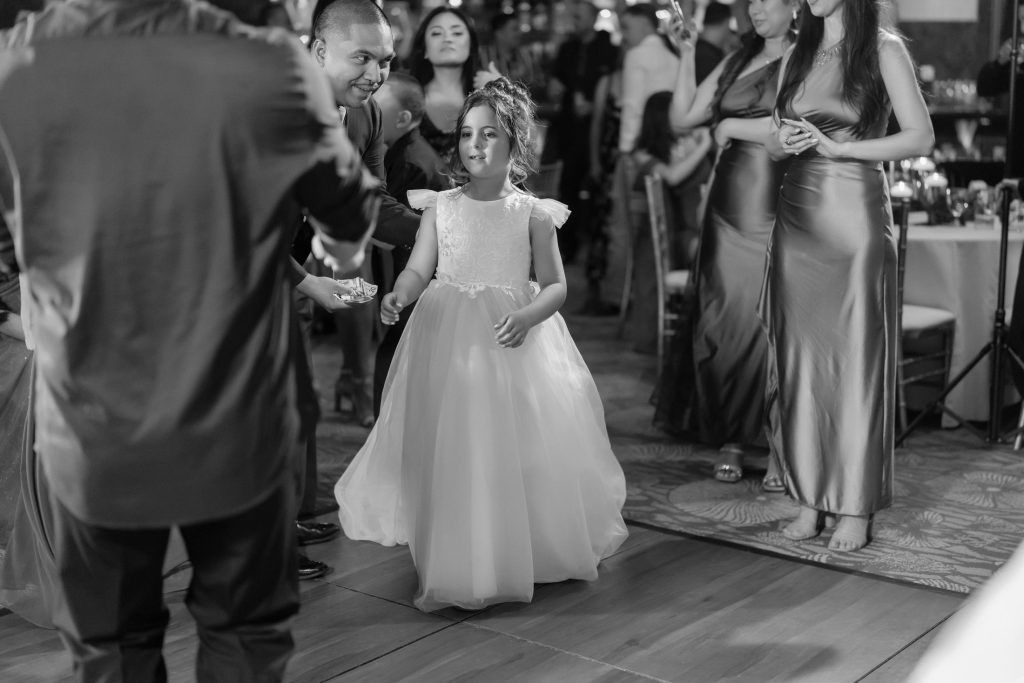 Flower girl dancing at wedding reception in black and white