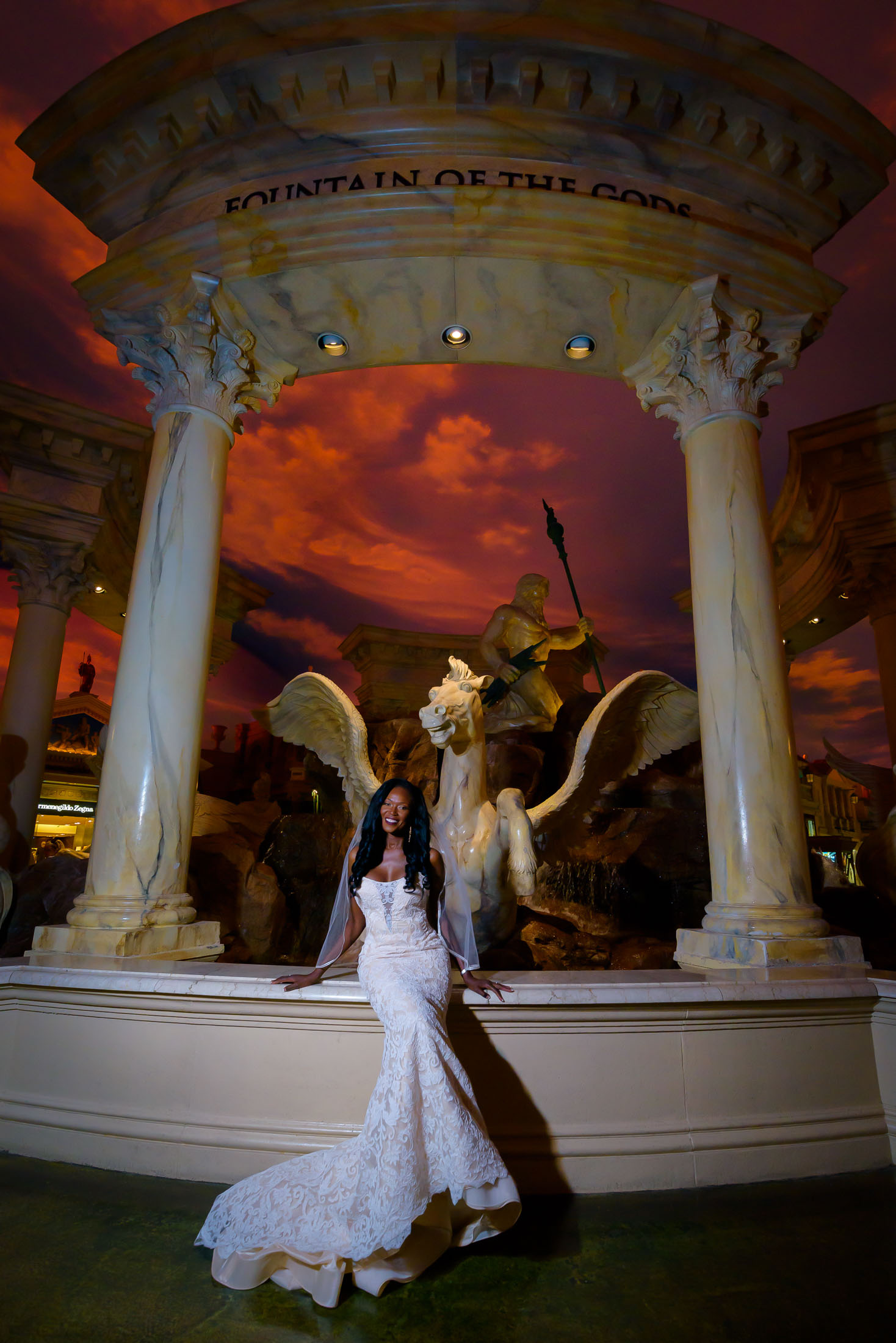 Las Vegas Strip elopement bride portrait at Caesars Palace Forum Shops with dramatic ceiling sky and statues at night, photographed by Zoltan Redl-Nagy