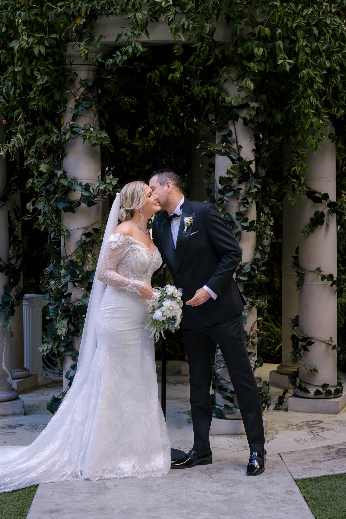 bride and groom sharing a kiss on the cheek during Las Vegas wedding ceremony at Caesars Palace Venus Garden photographed by Zoltan Redl Nagy