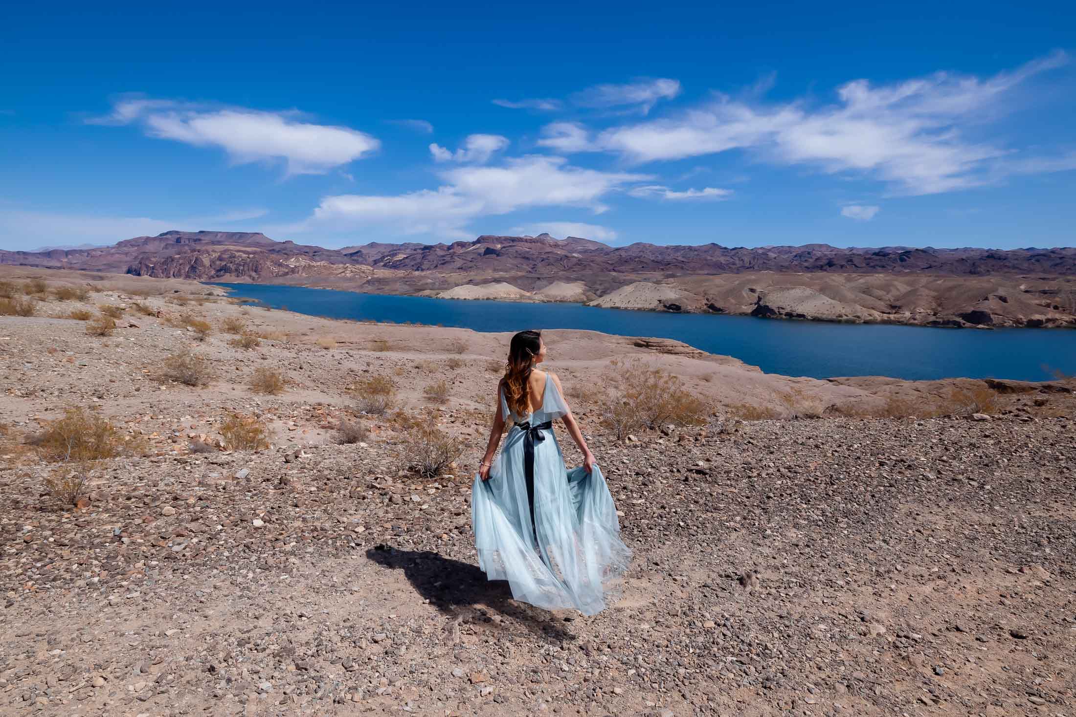 Bride walking in flowing dress above Colorado River desert landscape near Las Vegas Nevada elopement