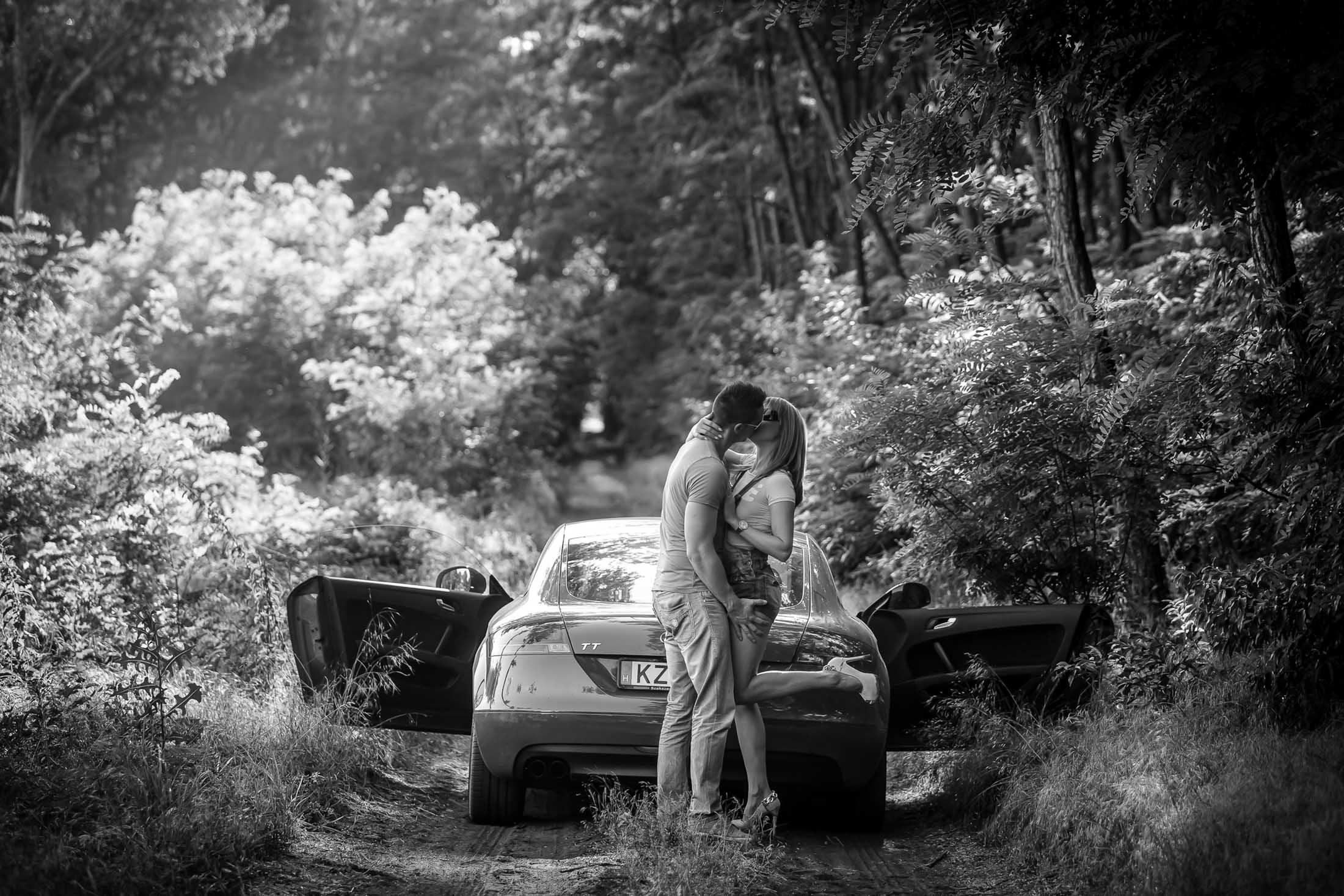 Engagement couple kissing by car in forest black and white romantic moment photographed by Zoltan Redl Nagy