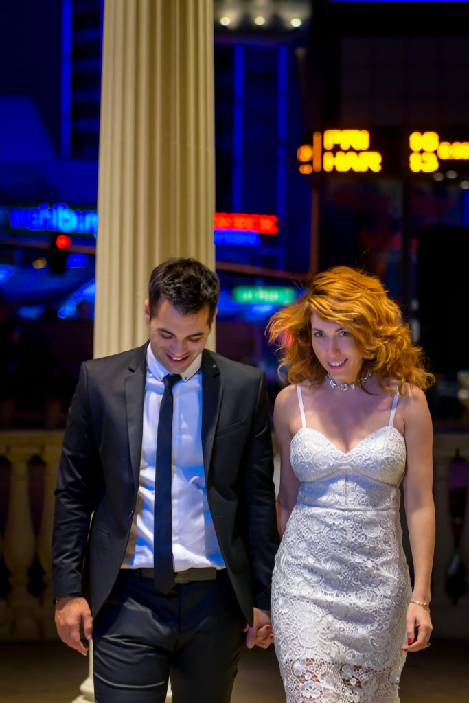 Las Vegas elopement couple walking together at Caesars Palace gazebo at night with city lights in background, photographed by Zoltan Redl-Nagy