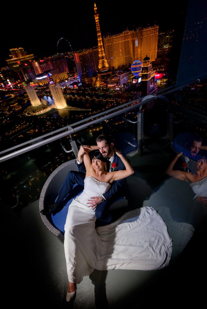 Bride and groom on a terrace overlooking the Las Vegas Strip and Bellagio fountains at night