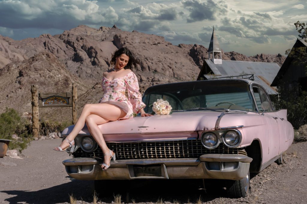 Bride sitting on pink vintage car at Nelson Ghost Town Nevada desert near Las Vegas