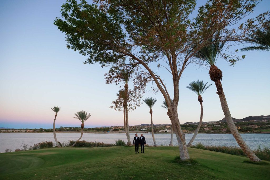 Same-sex wedding couple walking by Lake Las Vegas at The Westin resort during sunset