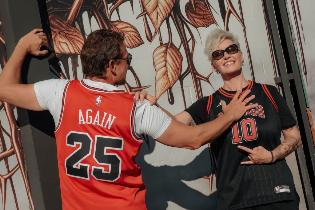 Renewal elopement couple in Las Vegas Arts District wearing basketball jerseys posing in front of artistic mural, photographed by Zoltan Redl Nagy.