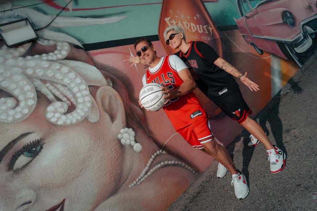Renewal elopement couple in Las Vegas Arts District holding a basketball in front of colorful street art mural, photographed by Zoltan Redl Nagy.
