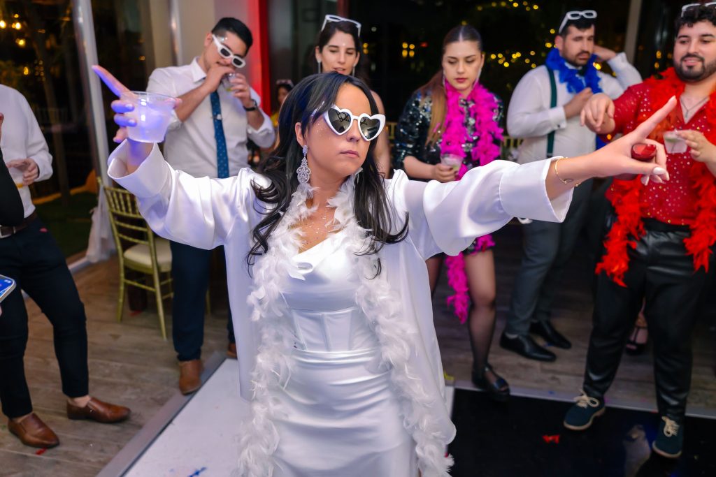 Same sex wedding reception bride dancing with guests and holding a drink in Las Vegas, photographed by Zoltan Redl Nagy.