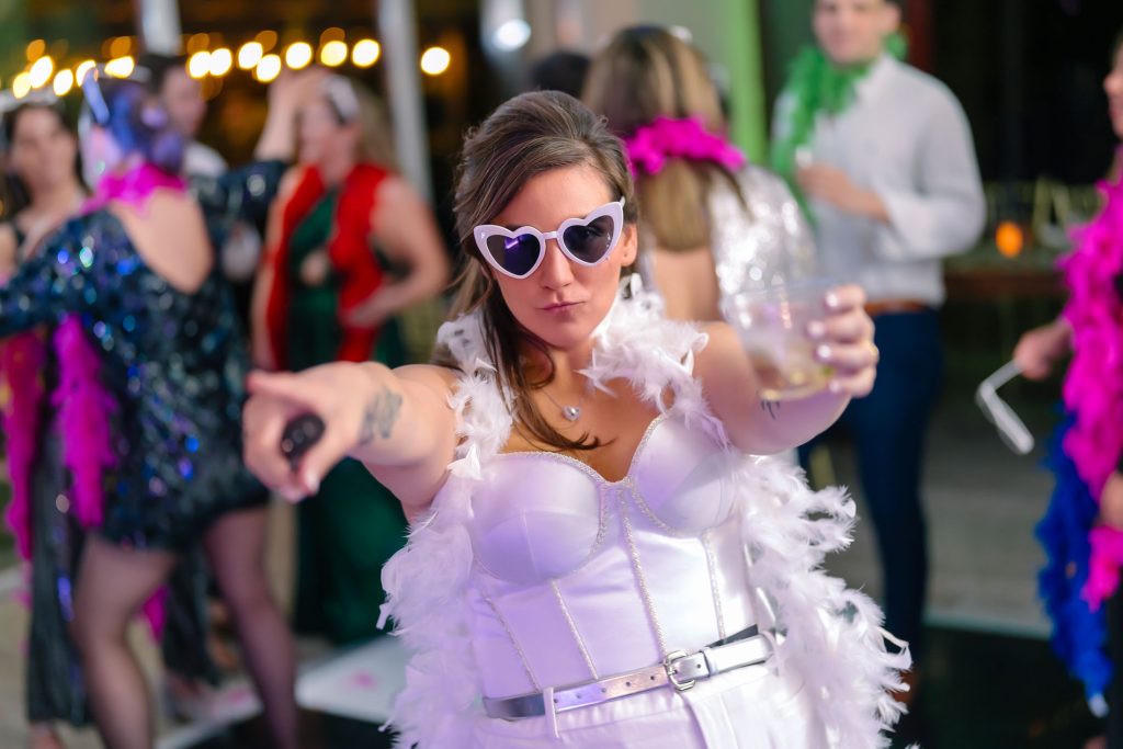 Same sex wedding reception bride dancing with drink and heart-shaped sunglasses in Las Vegas, photographed by Zoltan Redl Nagy.