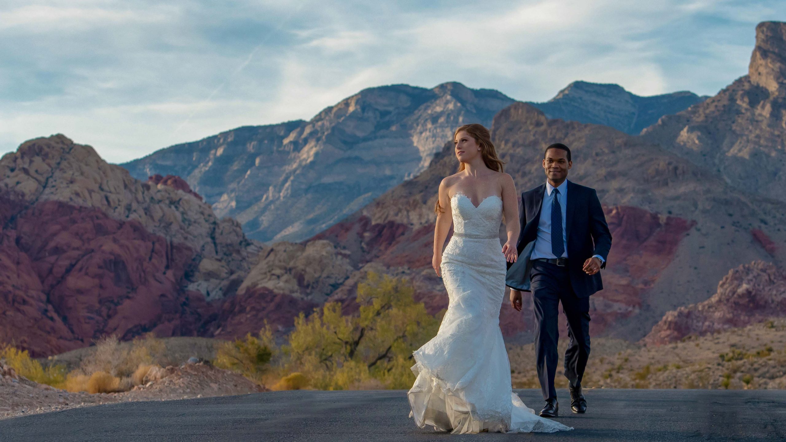 Bride and groom walking together through Red Rock Canyon Calico Basin with dramatic desert mountains in the background