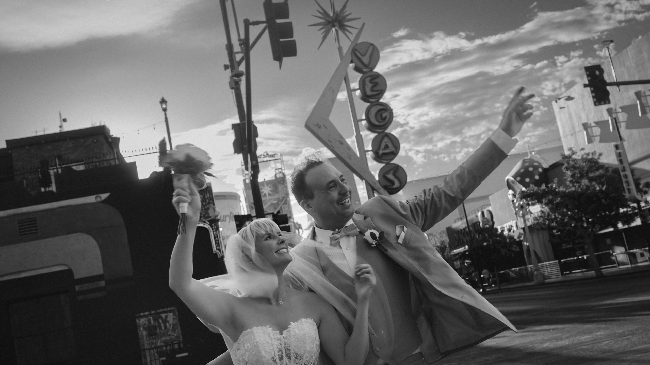 Las Vegas Downtown elopement couple celebrating beneath the iconic Vegas sign on Fremont East in a black and white wedding portrait.