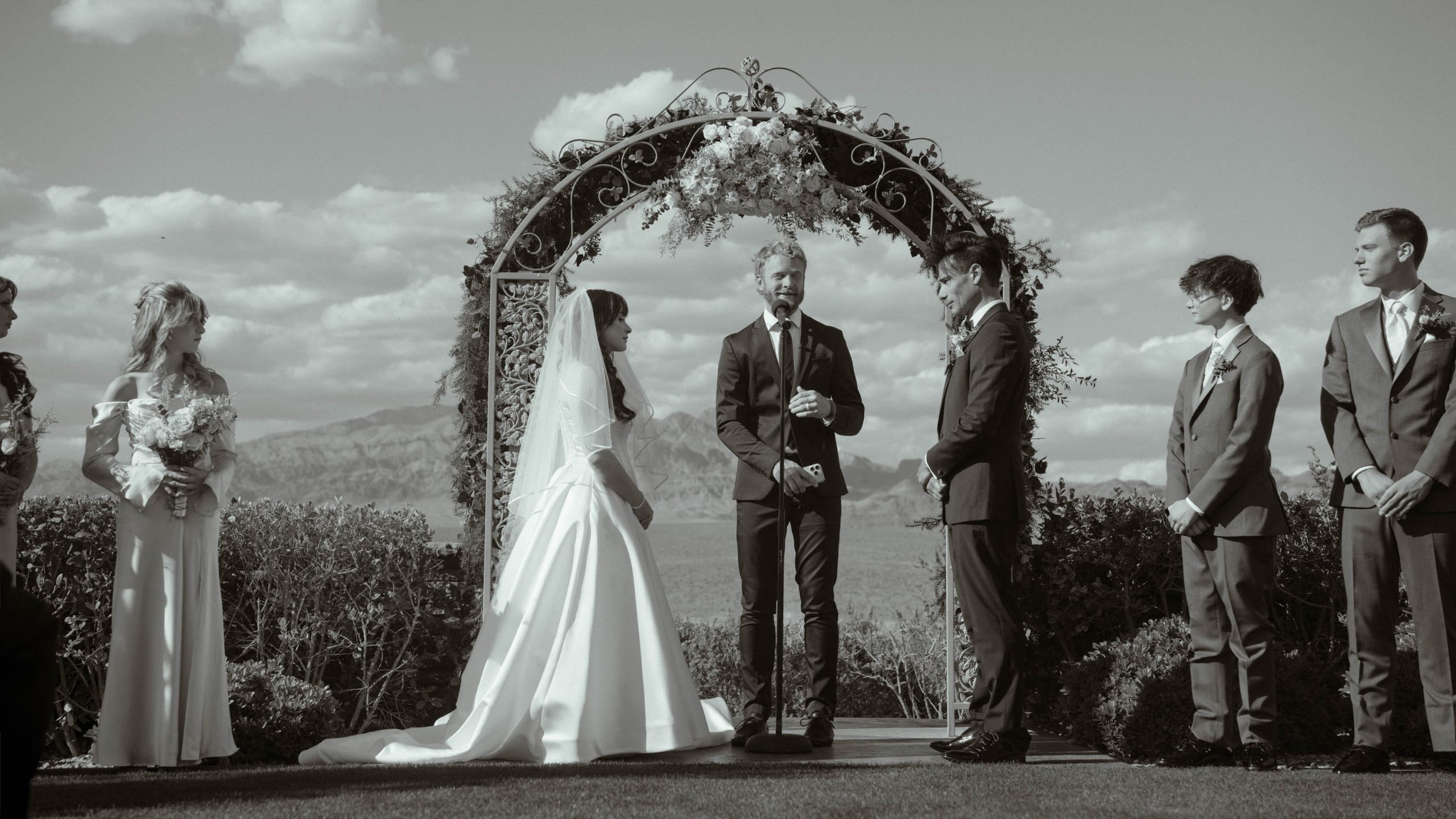 Bride and groom exchanging vows during an outdoor wedding ceremony at Las Vegas Paiute Golf Resort with mountain views in the background