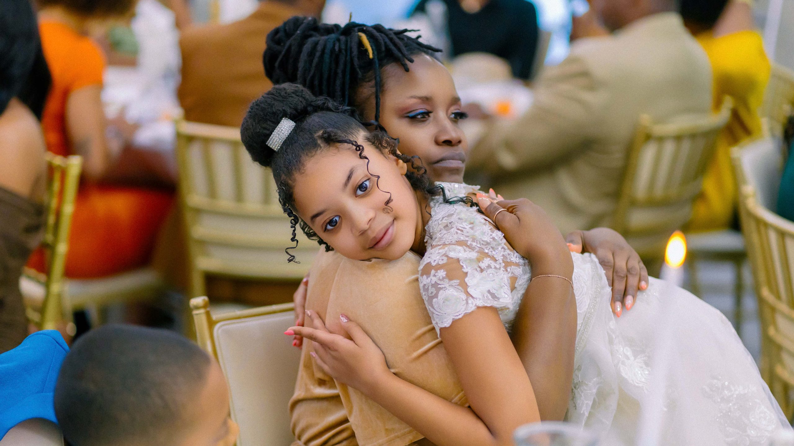 Young flower girl hugging a family member during an emotional wedding reception moment in Las Vegas