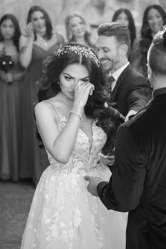 Emotional bride wiping tears during vows at Mandalay Bay Valley of the Falls wedding black and white