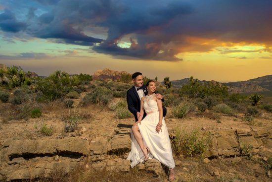 Red Rock Canyon elopement couple sitting on rocks at sunset with dramatic sky