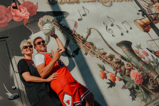 Renewal elopement couple in Las Vegas Arts District holding a basketball in front of colorful mural, photographed by Zoltan Redl Nagy.