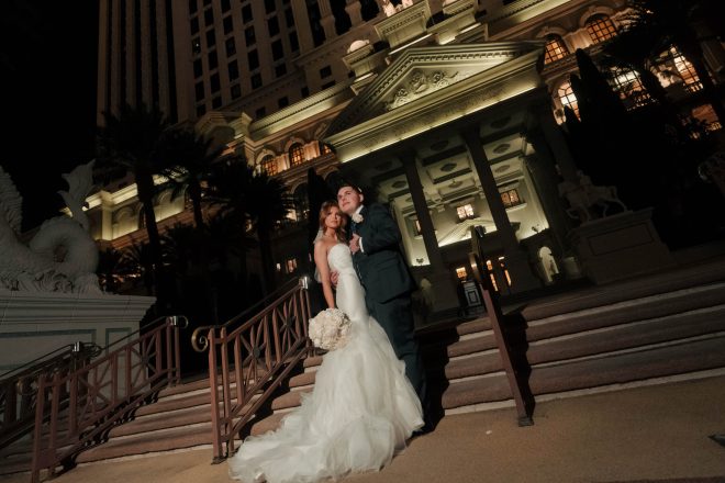 Wedding couple on stairs at Caesars Palace entrance at night Las Vegas