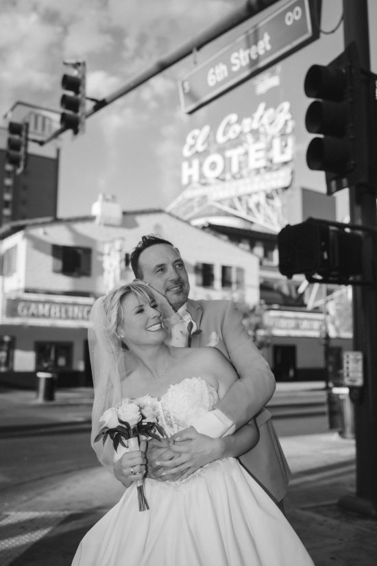 Romantic Las Vegas Downtown elopement couple embracing in front of the historic El Cortez Hotel on Fremont Street in a timeless black and white wedding portrait.