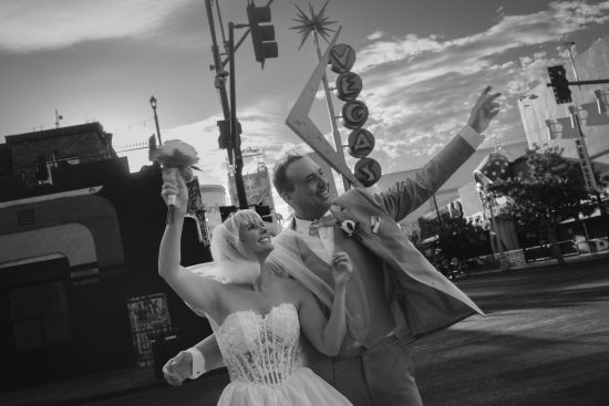 Las Vegas Downtown elopement couple celebrating beneath the iconic Vegas sign on Fremont East in a black and white wedding portrait.