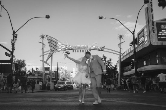 Las Vegas Downtown elopement couple kissing beneath the Fremont East District sign during a romantic black and white wedding portrait.