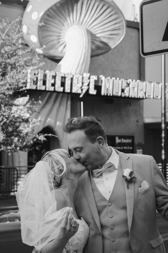 Las Vegas Downtown elopement couple sharing a romantic kiss in front of the iconic Electric Mushroom sign in a timeless black and white wedding portrait.