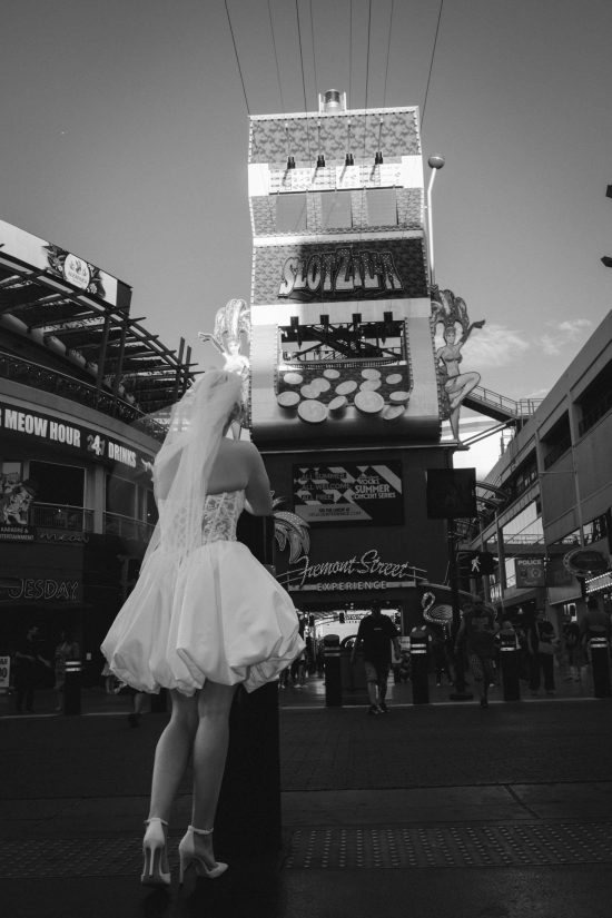 Bride walking toward the SlotZilla attraction during a Las Vegas Downtown elopement at the Fremont Street Experience in a timeless black and white portrait.