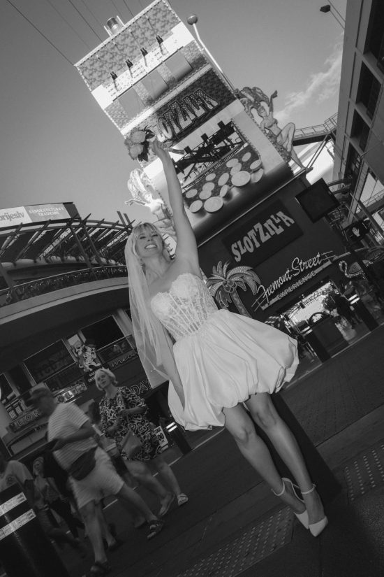 Bride celebrating her Las Vegas Downtown elopement in front of the SlotZilla attraction on Fremont Street in a timeless black and white portrait.