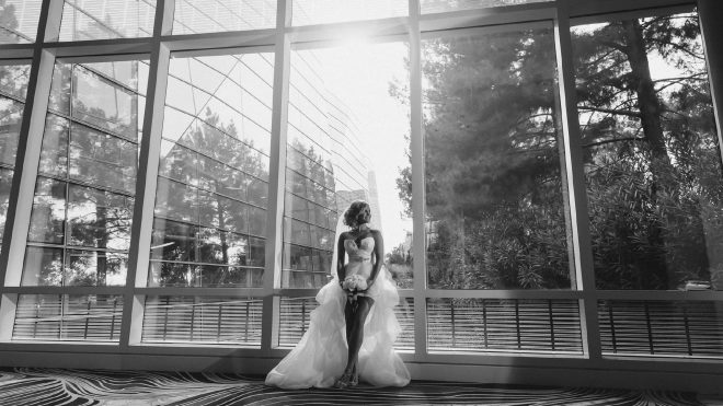 Black and white bridal portrait of a bride standing in front of floor-to-ceiling windows at ARIA Resort in Las Vegas.