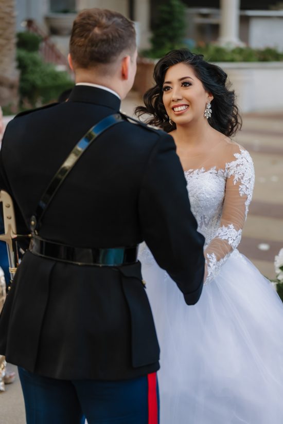 Bride and U.S. Marine groom exchanging vows during a luxury outdoor wedding ceremony at Caesars Palace in Las Vegas.