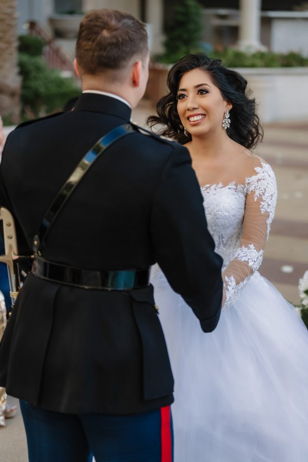 Bride and U.S. Marine groom exchanging vows during a luxury outdoor wedding ceremony at Caesars Palace in Las Vegas.