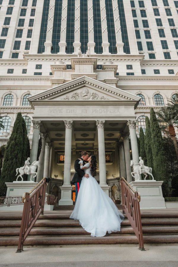 Luxury Caesars Palace wedding couple kissing on the grand staircase beneath the iconic Roman architecture in Las Vegas.