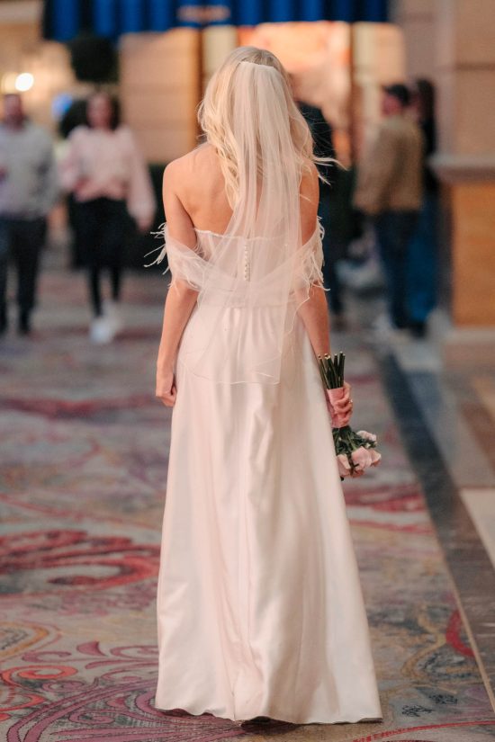Bride walking through Paris Las Vegas with bouquet after her romantic Las Vegas elopement.