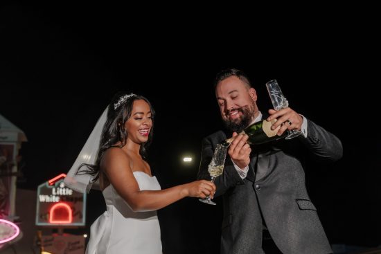 Bride and groom celebrating with champagne outside Little White Chapel at night in Las Vegas