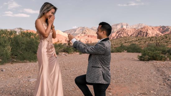 Surprise marriage proposal at Red Rock Canyon with colorful desert mountains in the background.